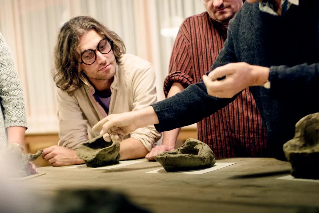 Dozent der Waldorfpädagogik zeigt aus Lehm geformte Objekte Studenten