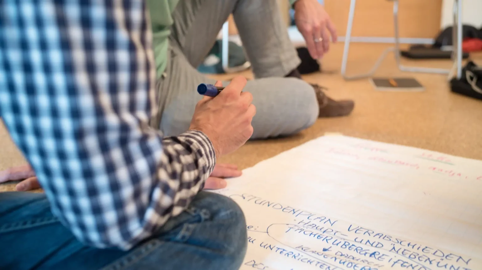 Zwei Studierende bringen Notizen auf ein großes Poster am Boden