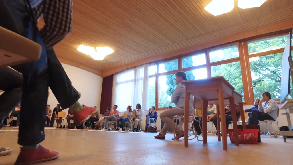 Studenten der Waldorfpädagogik in Dornach sitzen im Stuhlkreis um Dozierenden