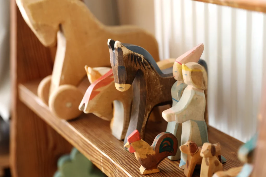 Bunte Holzfiguren und Holztiere auf einem Regal