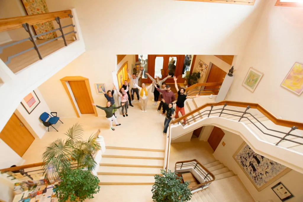 Studenten und Dozenten im Treppenhaus der Akademie für anthroposophische Pädagogik strecken die Hände der Kamera entgegen